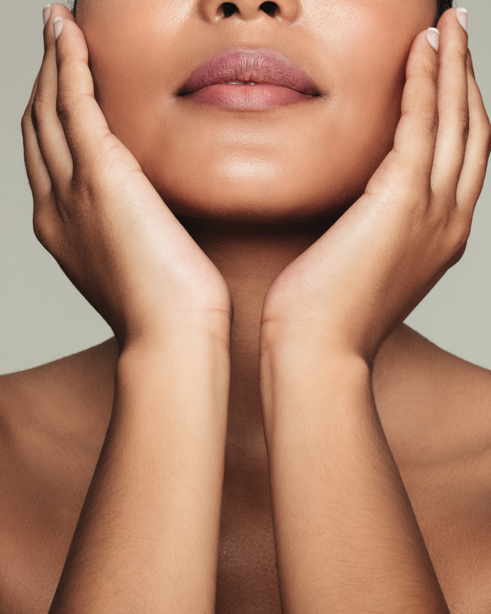 A woman's lower face and hands with smooth glowing skin